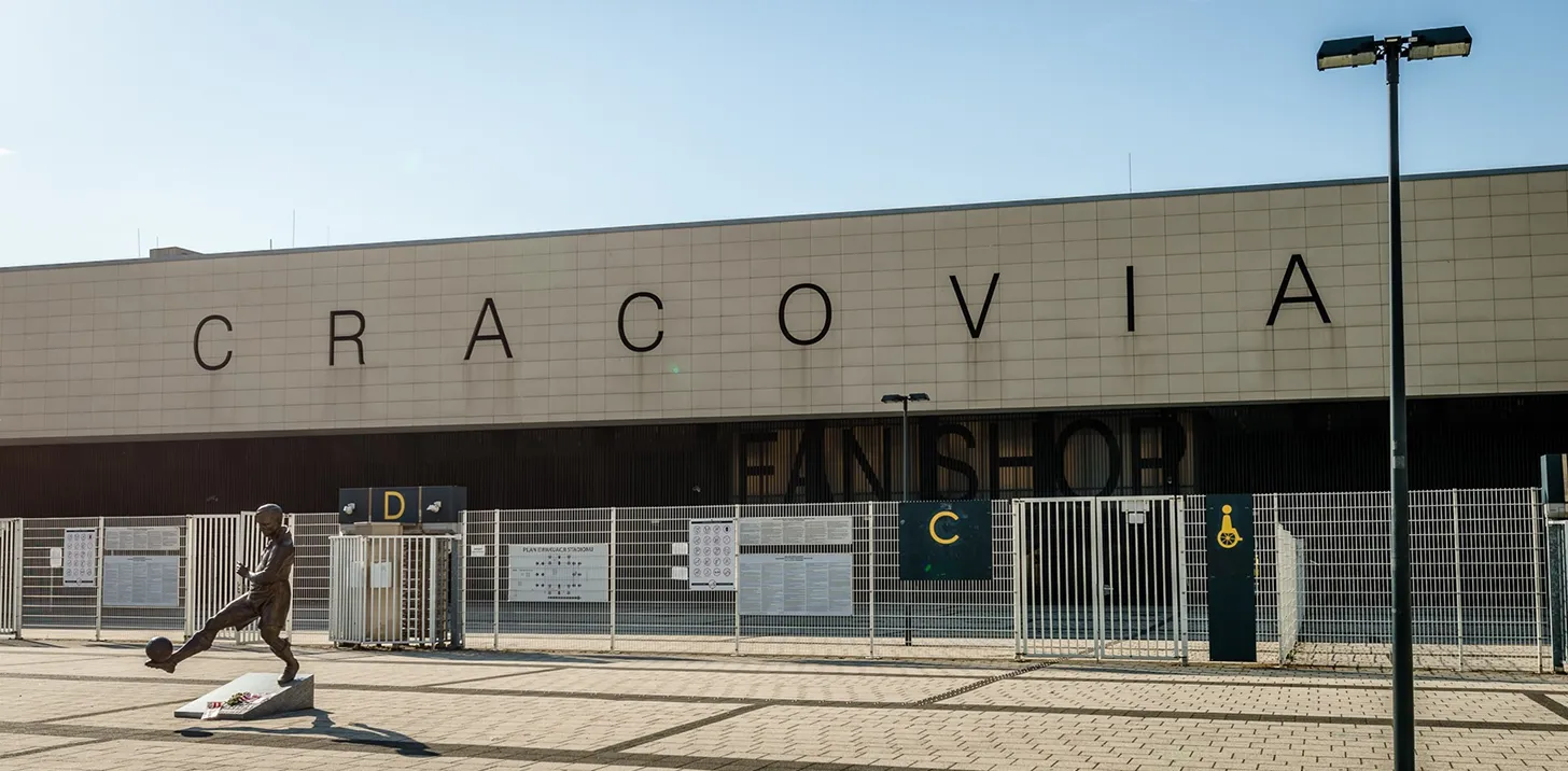 Fasada stadionu Cracovii z napisem „CRACOVIA” i wejściem do Fan Shopu.